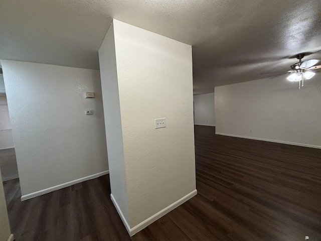 corridor with a textured ceiling and dark hardwood / wood-style floors