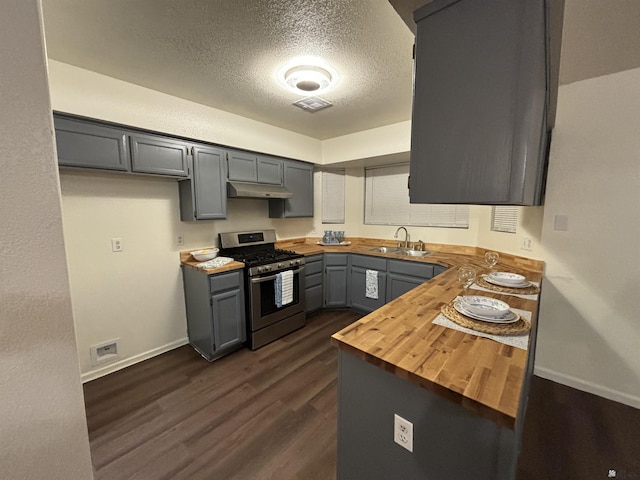 kitchen featuring gray cabinetry, sink, stainless steel gas range oven, butcher block countertops, and a textured ceiling