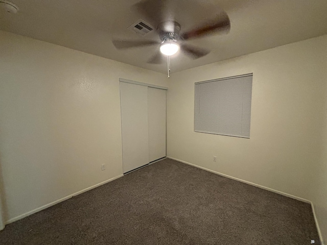 unfurnished bedroom featuring ceiling fan, a closet, and dark colored carpet