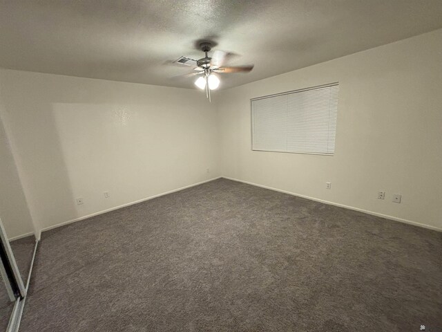 carpeted spare room featuring a textured ceiling and ceiling fan