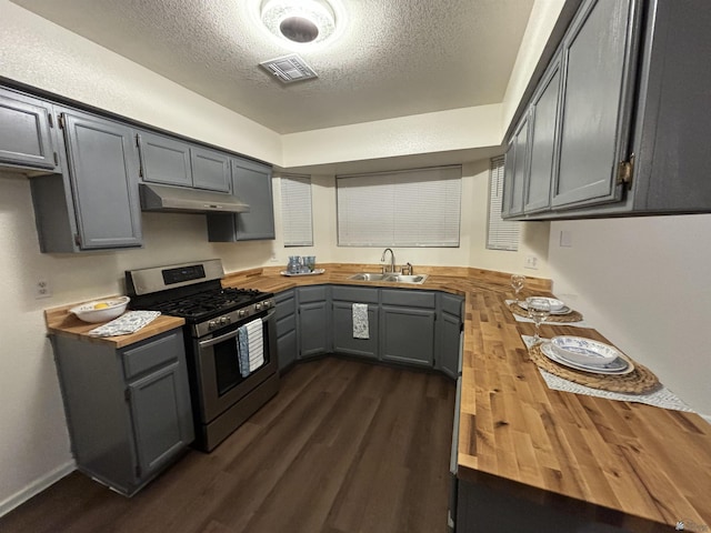 kitchen featuring stainless steel gas range oven, sink, gray cabinets, and wood counters