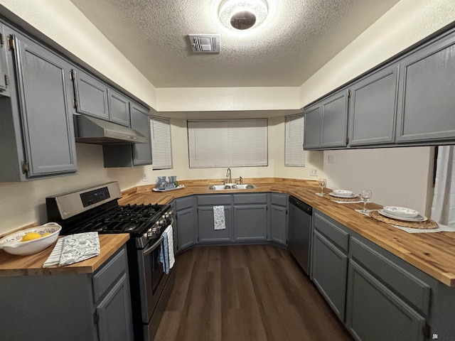 kitchen featuring appliances with stainless steel finishes, butcher block countertops, gray cabinetry, and sink