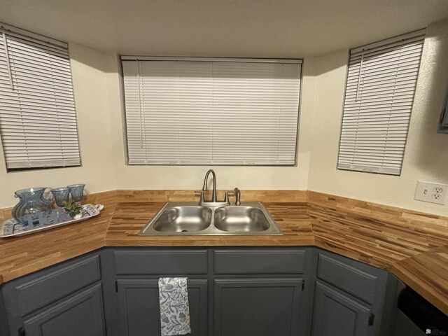 kitchen with butcher block countertops, gray cabinets, and sink