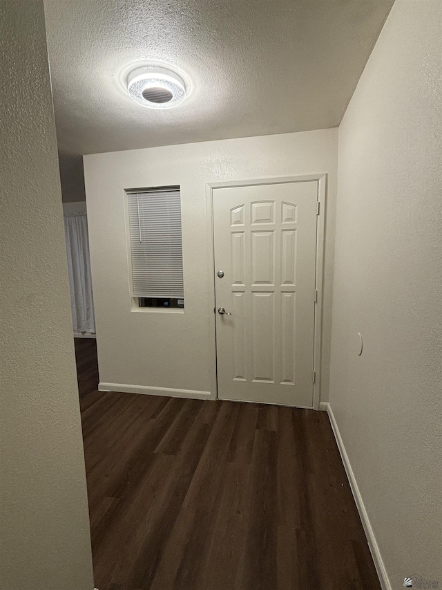 hall with dark hardwood / wood-style floors and a textured ceiling