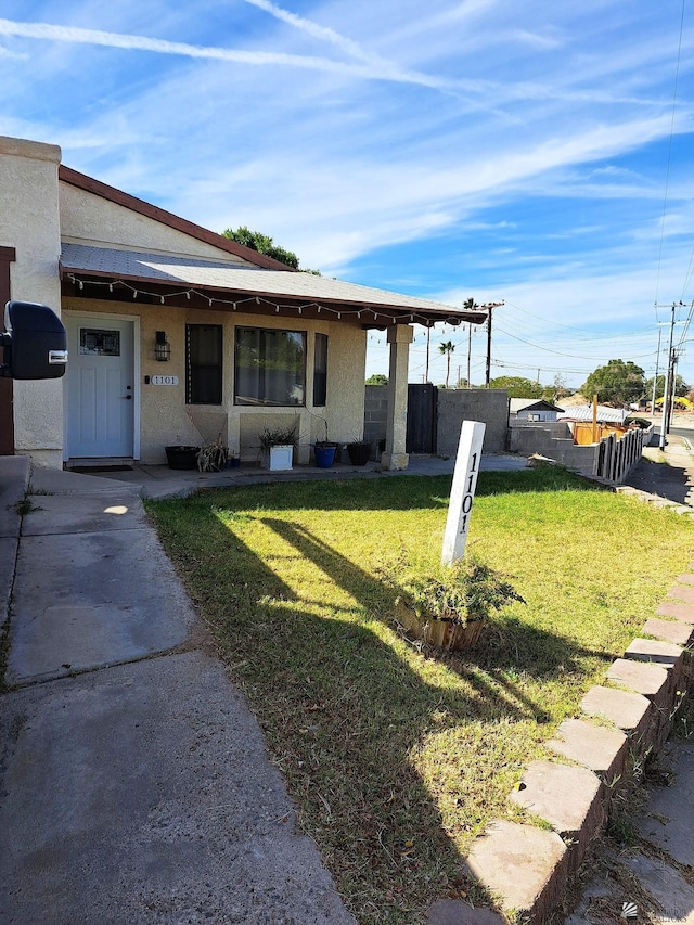 view of front of home with fence, a front lawn, and stucco siding