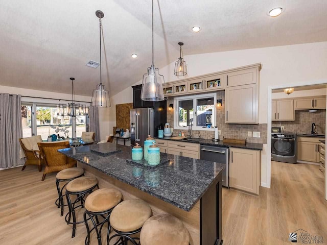 kitchen with a center island, decorative light fixtures, lofted ceiling, and appliances with stainless steel finishes