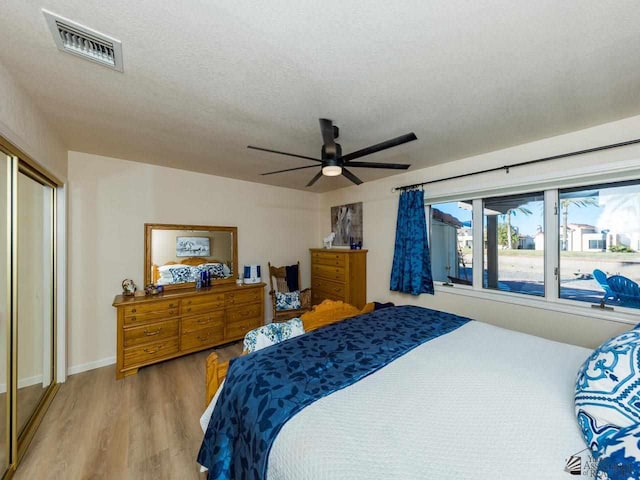 bedroom featuring ceiling fan, light wood-type flooring, a textured ceiling, and a closet