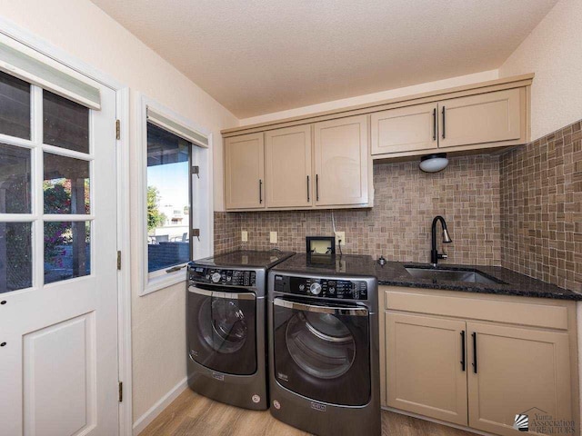 clothes washing area with cabinets, light wood-type flooring, separate washer and dryer, and sink