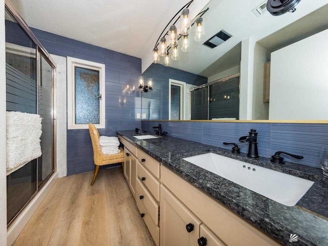 bathroom featuring backsplash, wood-type flooring, an enclosed shower, vanity, and tile walls