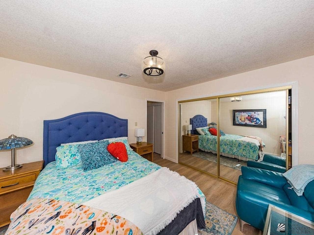 bedroom featuring a closet, a textured ceiling, and hardwood / wood-style flooring