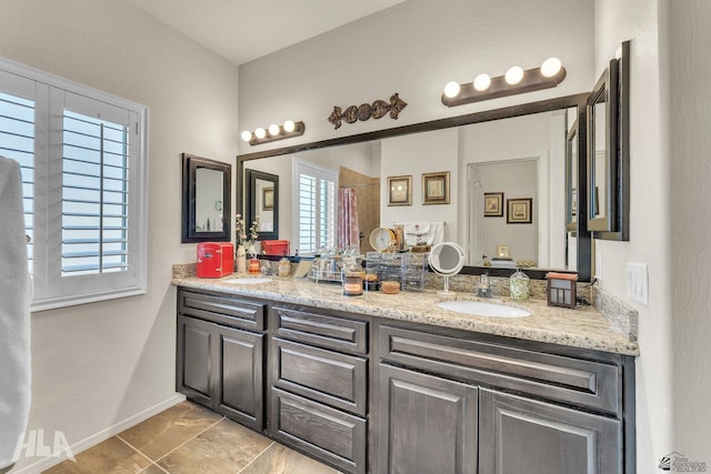 full bathroom with a sink, baseboards, and double vanity