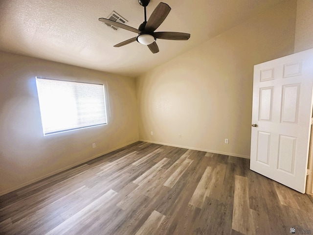 unfurnished room featuring a textured ceiling, ceiling fan, wood finished floors, baseboards, and vaulted ceiling