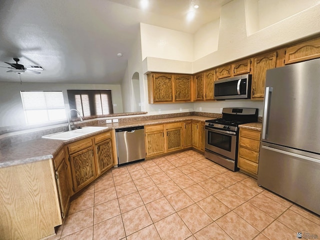 kitchen with light tile patterned floors, ceiling fan, stainless steel appliances, a sink, and brown cabinets