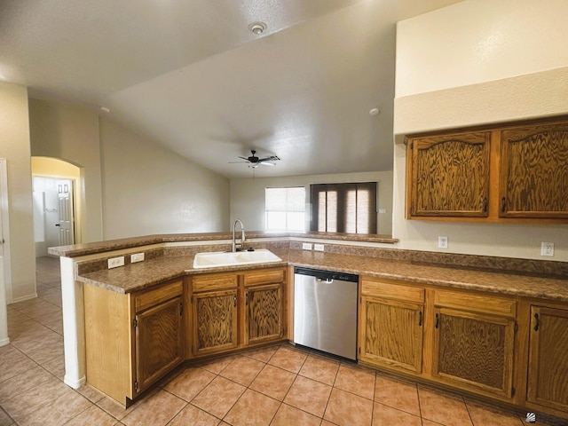 kitchen featuring arched walkways, light tile patterned flooring, a sink, vaulted ceiling, and stainless steel dishwasher