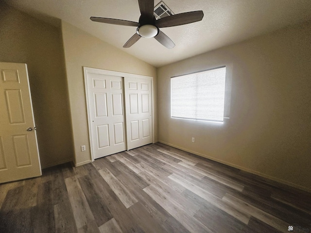 unfurnished bedroom with lofted ceiling, ceiling fan, wood finished floors, baseboards, and a closet