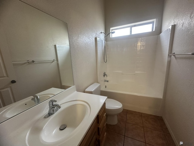 bathroom with toilet, a textured wall, tile patterned flooring, and vanity