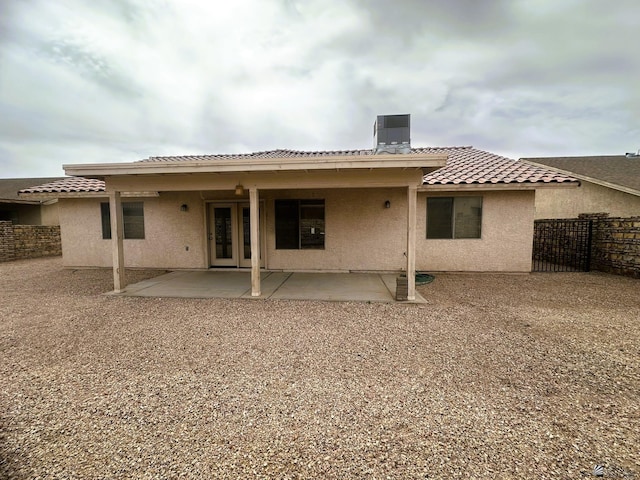 rear view of property featuring a patio, a tile roof, fence, and stucco siding