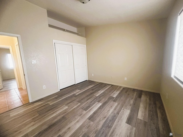 unfurnished bedroom featuring a closet, wood finished floors, and baseboards