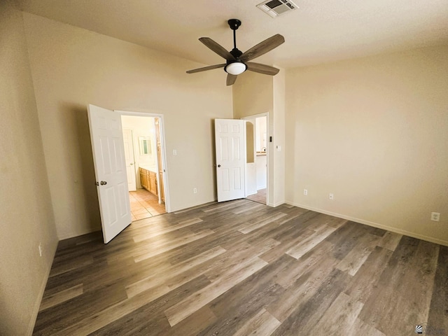 unfurnished bedroom with visible vents, ensuite bathroom, ceiling fan, wood finished floors, and high vaulted ceiling