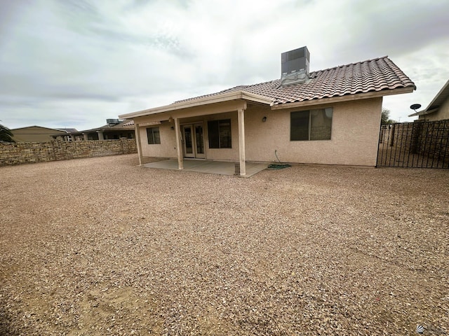 rear view of house featuring stucco siding, a patio, a tiled roof, and fence