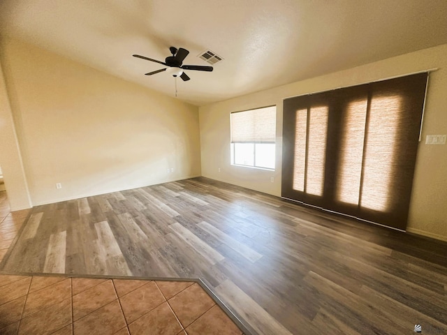 spare room featuring ceiling fan, visible vents, and wood finished floors