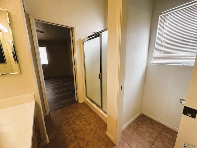 full bathroom featuring a stall shower, tile patterned flooring, baseboards, and vanity