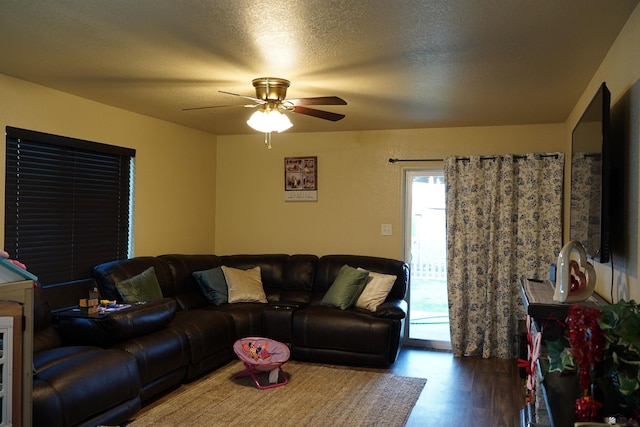 living room featuring ceiling fan, dark hardwood / wood-style floors, and a textured ceiling