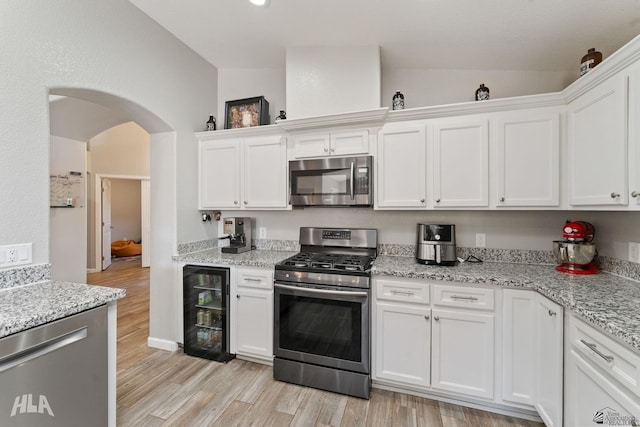 kitchen with white cabinetry, stainless steel appliances, wine cooler, and vaulted ceiling