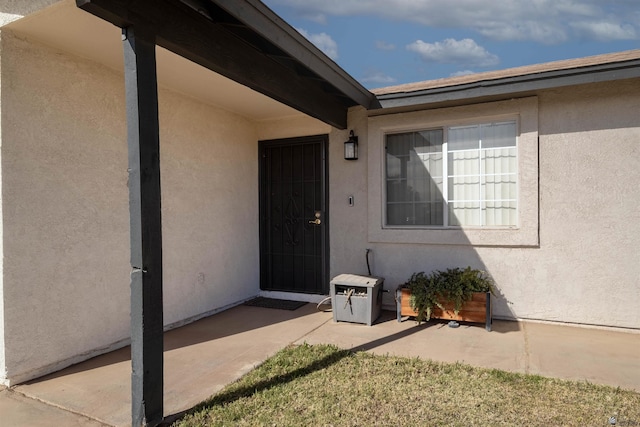 view of exterior entry with a patio