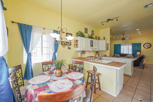 dining room featuring light tile patterned floors, sink, and ceiling fan with notable chandelier