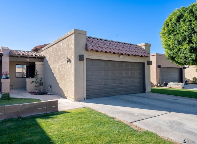 view of front of home featuring driveway, a tile roof, an attached garage, a front lawn, and stucco siding