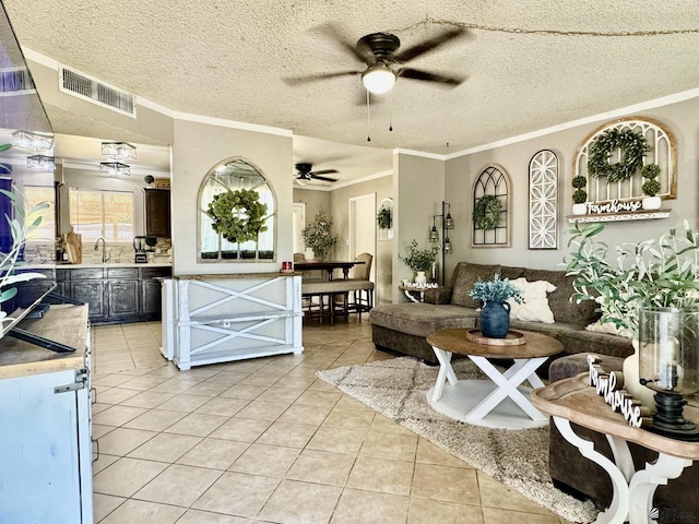 tiled living room with crown molding, sink, ceiling fan, and a textured ceiling