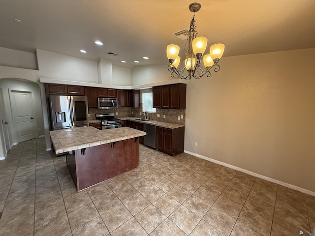 kitchen with stainless steel appliances, sink, decorative backsplash, hanging light fixtures, and a chandelier