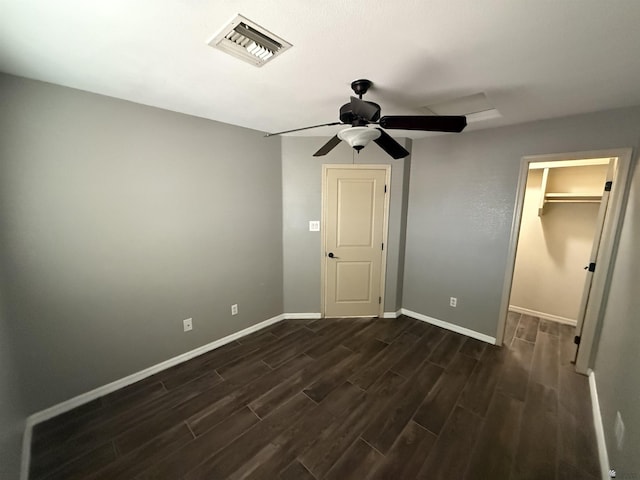 unfurnished bedroom featuring ceiling fan, a spacious closet, a closet, and dark hardwood / wood-style floors