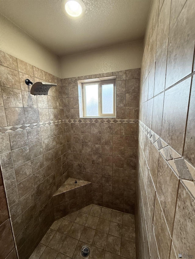 bathroom with a textured ceiling and a tile shower