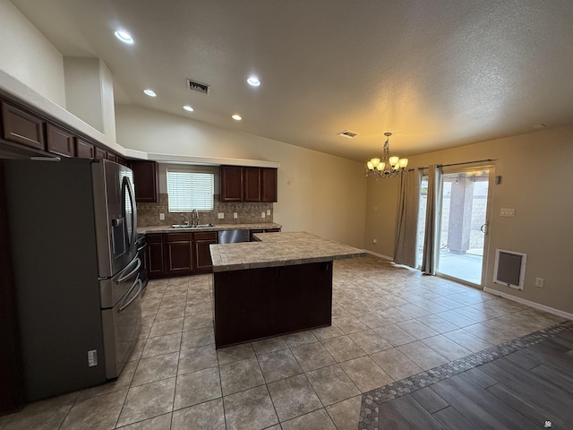 kitchen featuring a center island, hanging light fixtures, stainless steel appliances, decorative backsplash, and sink