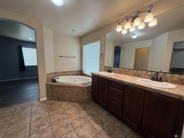 bathroom featuring a healthy amount of sunlight, vanity, tile patterned flooring, and tiled bath