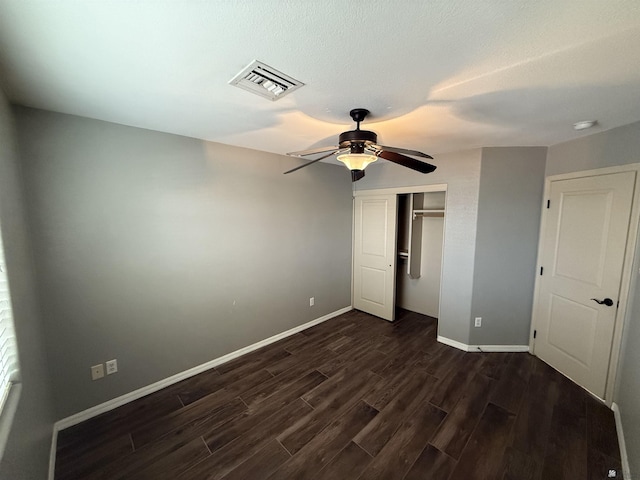 unfurnished bedroom with ceiling fan, dark wood-type flooring, and a closet