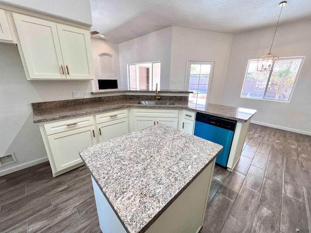 kitchen featuring sink, light stone counters, a kitchen island, decorative light fixtures, and stainless steel dishwasher