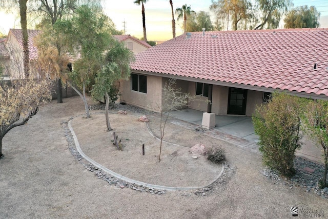 back house at dusk featuring a patio area