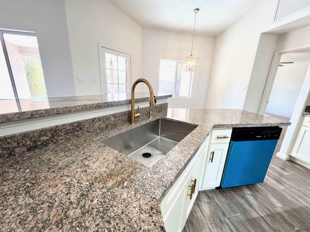 kitchen with stone countertops, pendant lighting, white cabinetry, sink, and stainless steel dishwasher