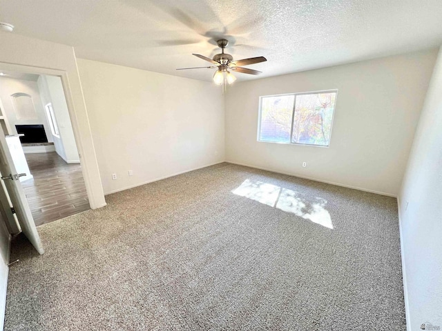 empty room with ceiling fan, a textured ceiling, and carpet flooring