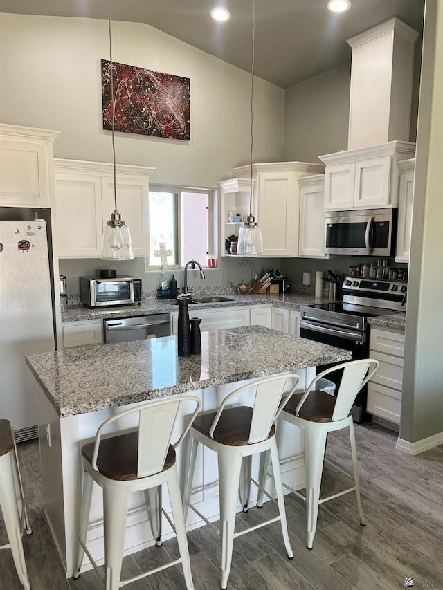 kitchen featuring sink, hanging light fixtures, light stone counters, white cabinetry, and stainless steel appliances