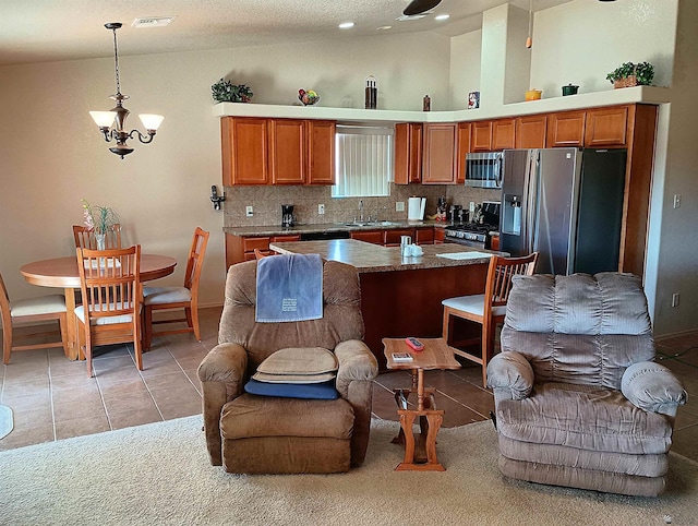 kitchen featuring appliances with stainless steel finishes, open floor plan, decorative light fixtures, and visible vents