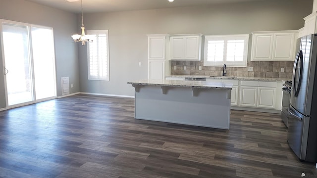 kitchen featuring white cabinetry, a kitchen island, stainless steel appliances, and decorative light fixtures