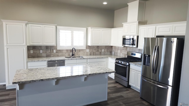 kitchen featuring appliances with stainless steel finishes, white cabinetry, a kitchen island, and sink