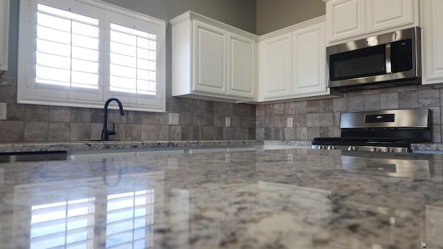 kitchen featuring decorative backsplash, light stone counters, white cabinetry, and stainless steel appliances