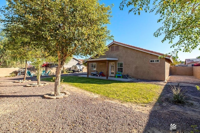 back of house featuring a fenced backyard, a yard, a patio, and stucco siding