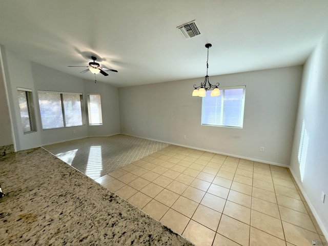 unfurnished room featuring ceiling fan with notable chandelier, visible vents, baseboards, and light tile patterned flooring