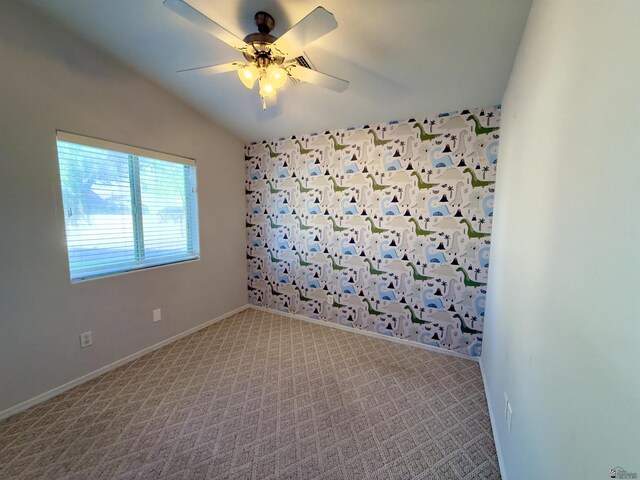 empty room featuring lofted ceiling, light colored carpet, ceiling fan, and baseboards